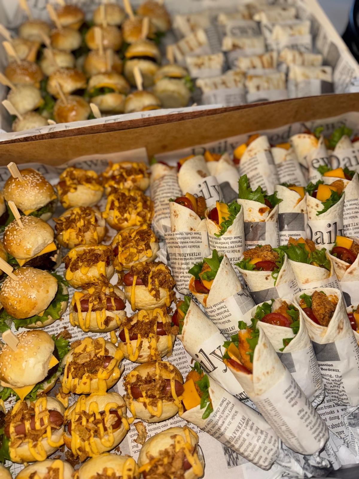 Schalen met mini burgers, hotdogs en gevulde wraps