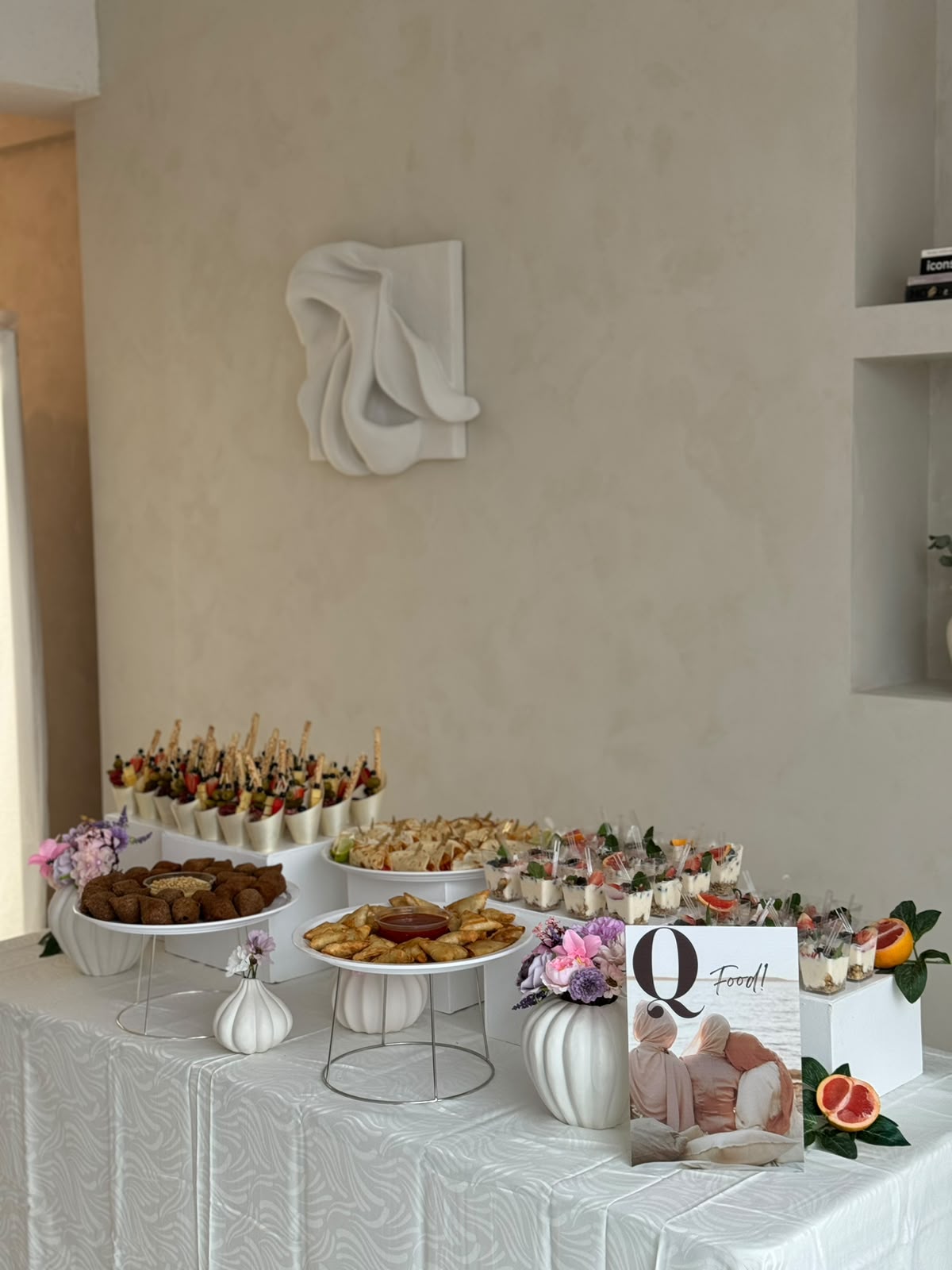 Wit gestyled buffet met borrelcups, kibbeh en roze bloemen
