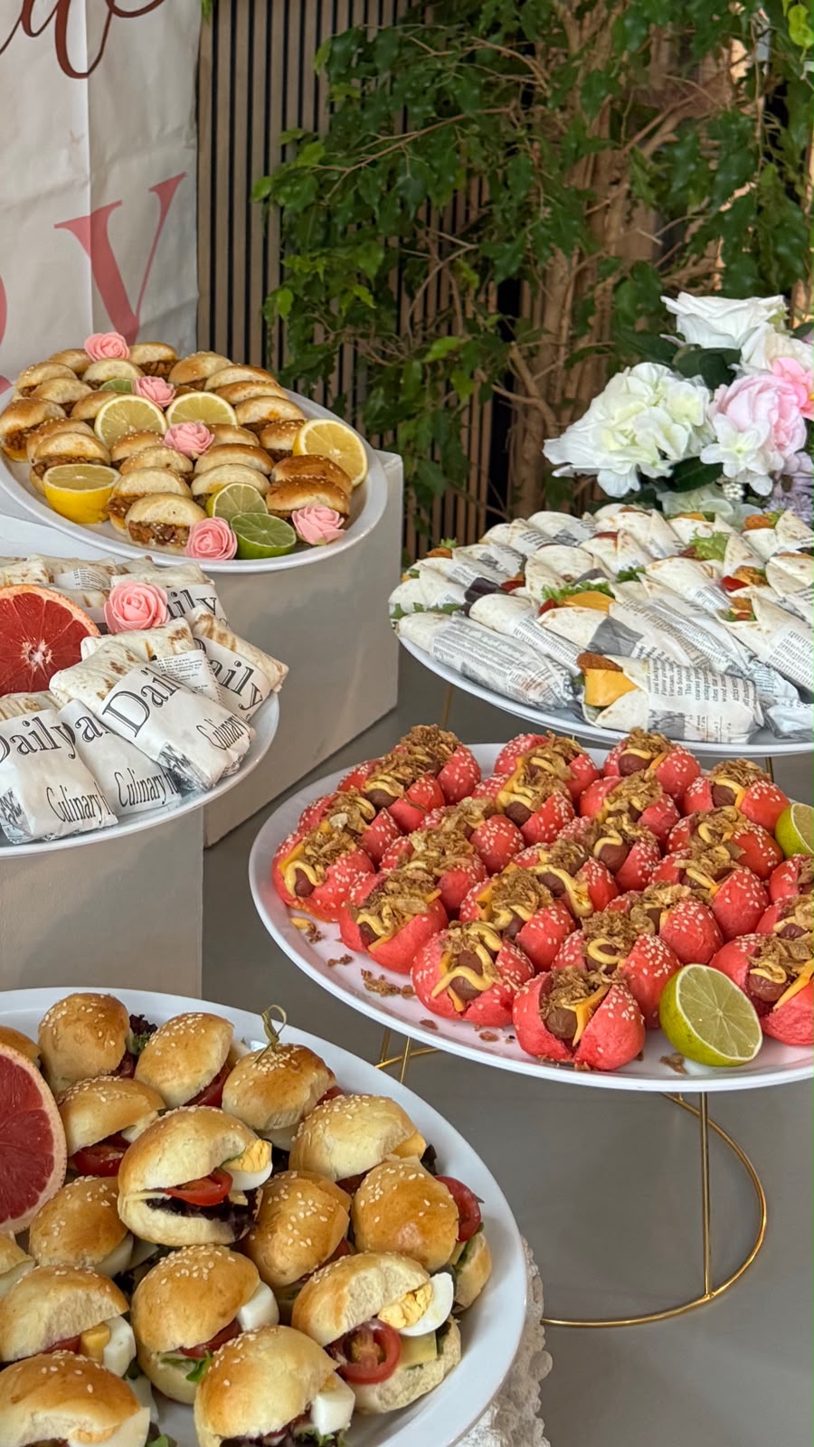 Buffet met roze bloemen, aardbeien en schalen hapjes