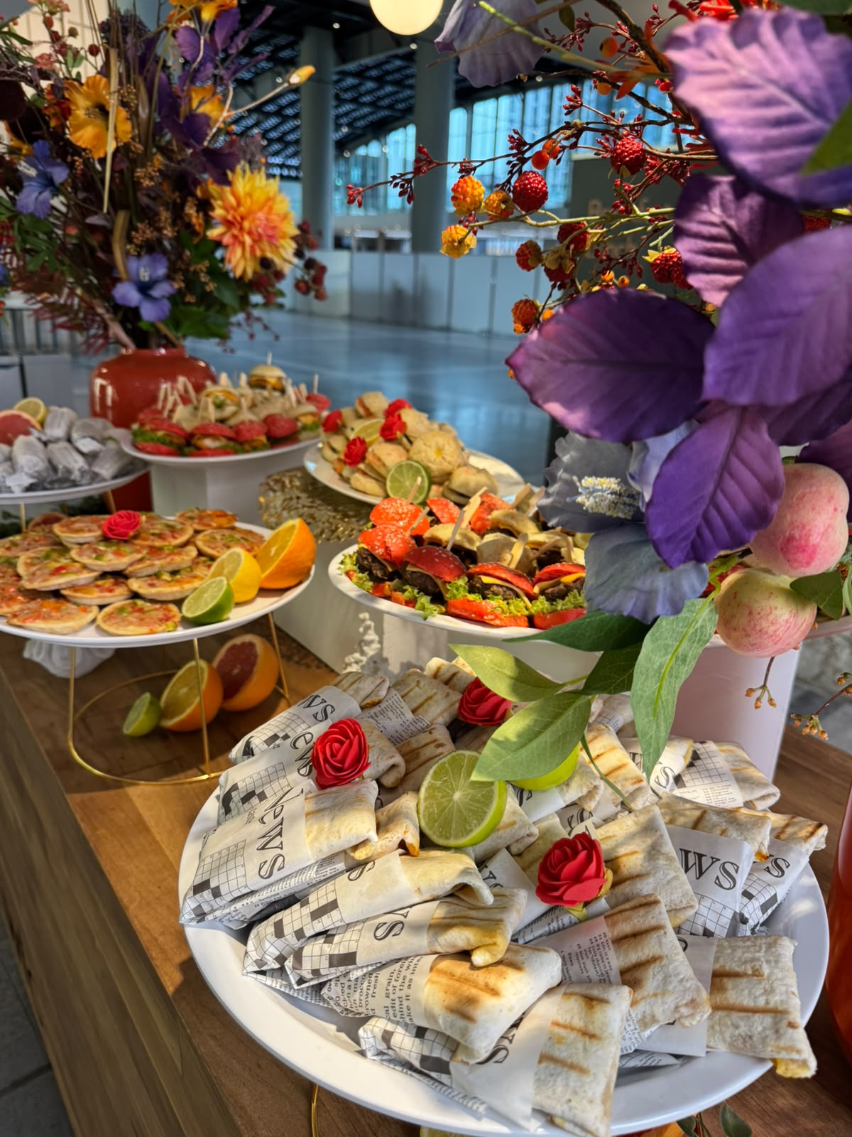 Feestelijk buffet met paarse bloemen en schalen op standaards
