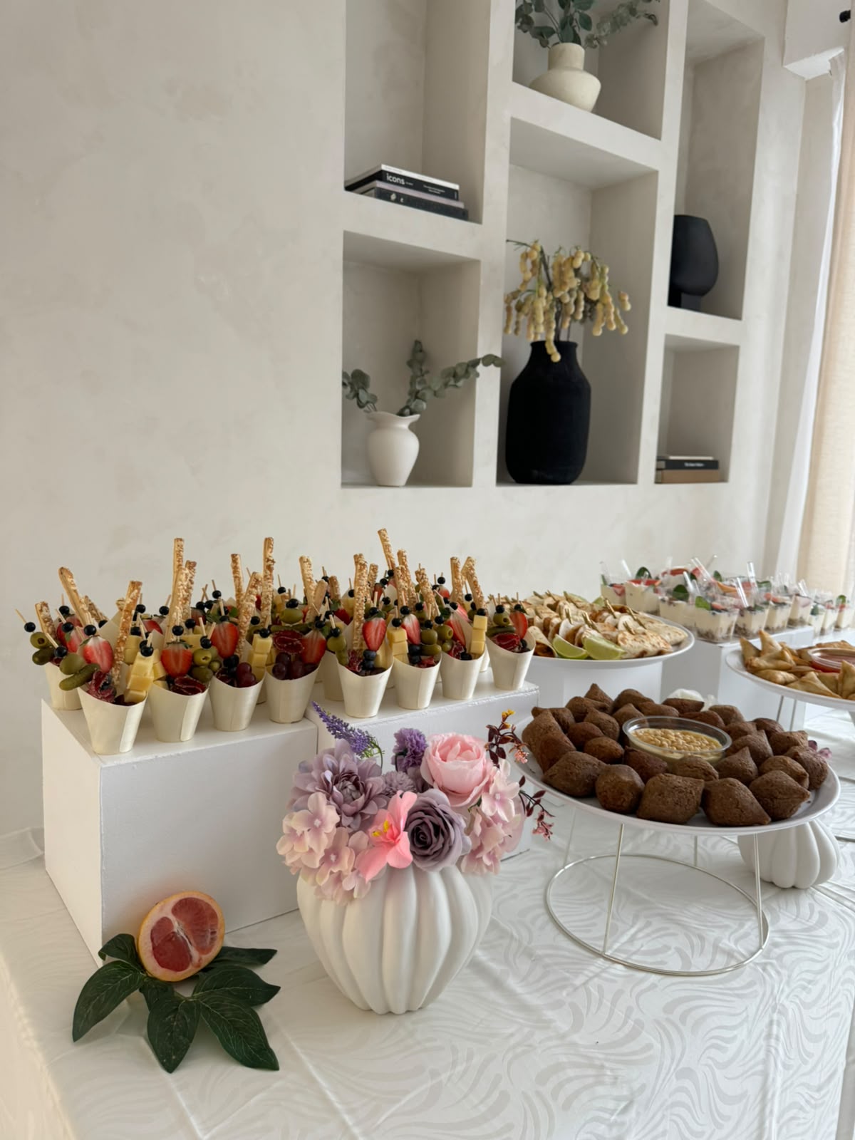 Wit buffet met borrelcups, samosa en bloemen op sokkels
