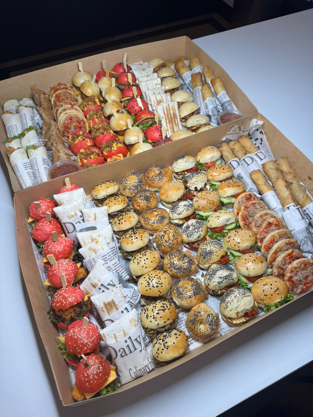 Grote hapjesbox met bagels, mini burgers en wraps naast elkaar