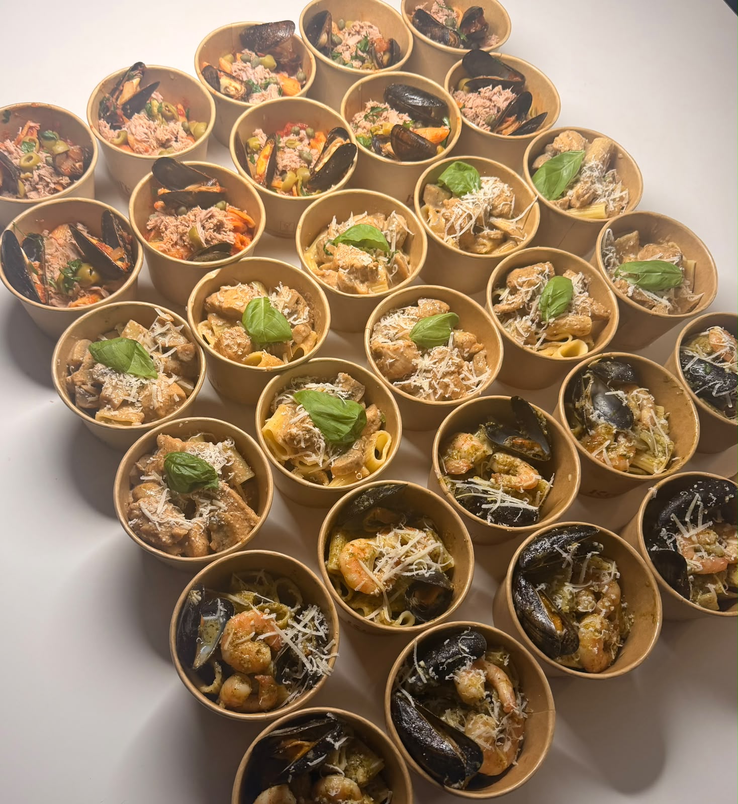 Pastacups van bovenaf, met basilicum en geraspte kaas