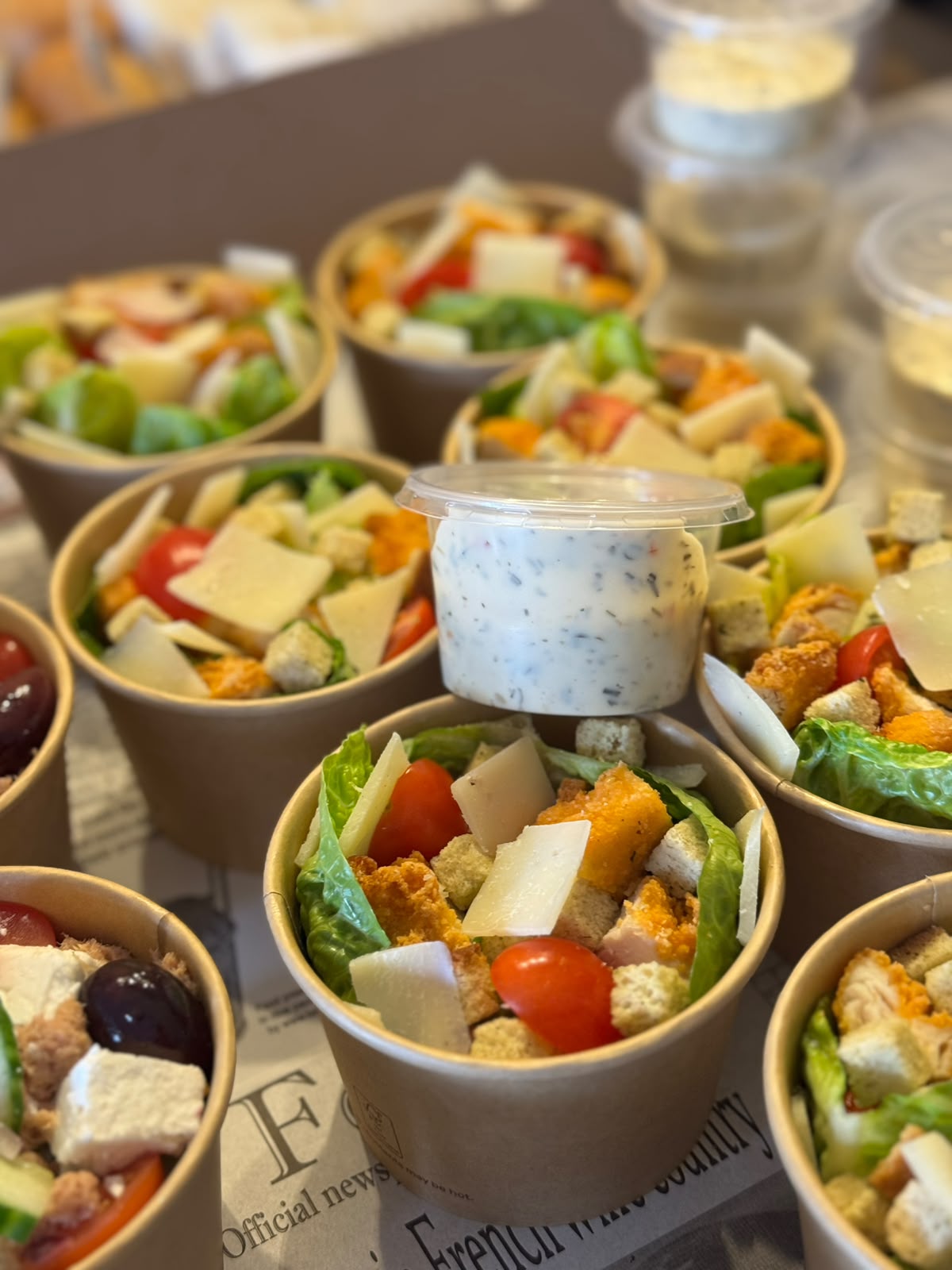 Salade cups met dressing, klaargezet op krantenpapier