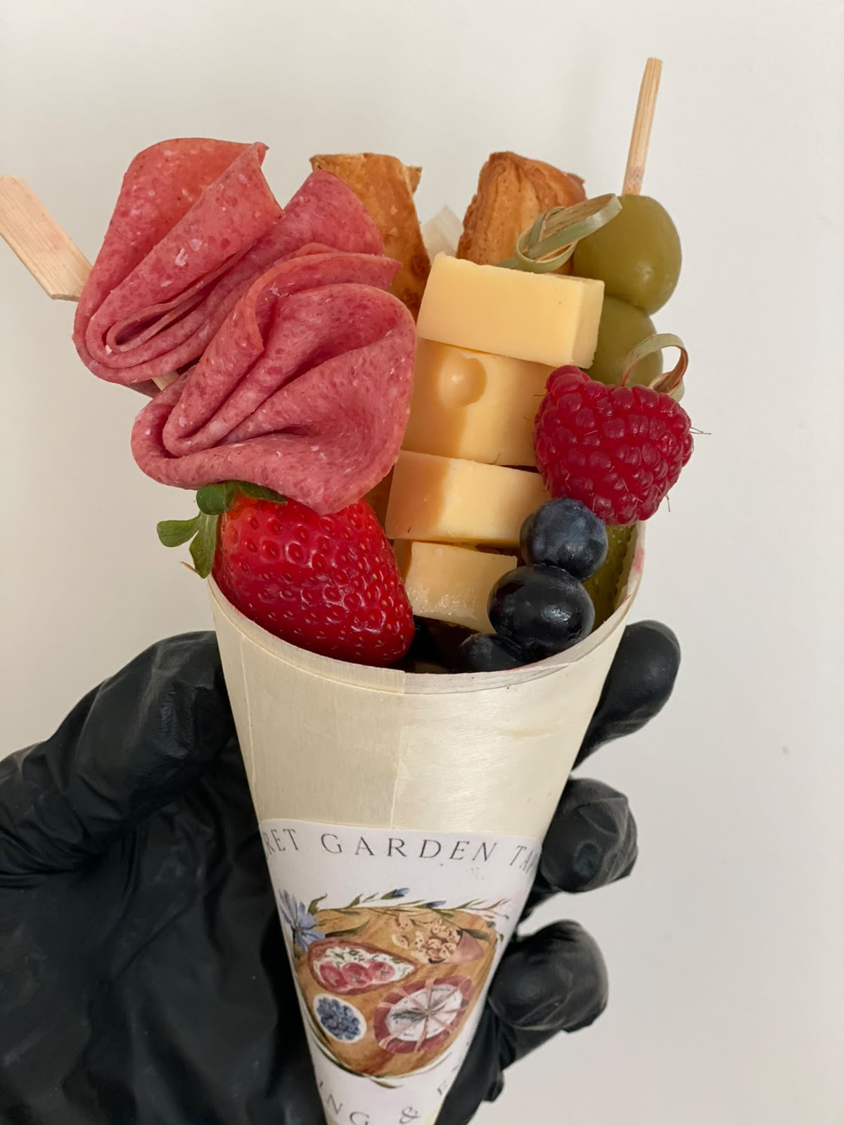 Borrelcup met salami, kaas, aardbei en grissini, in de hand